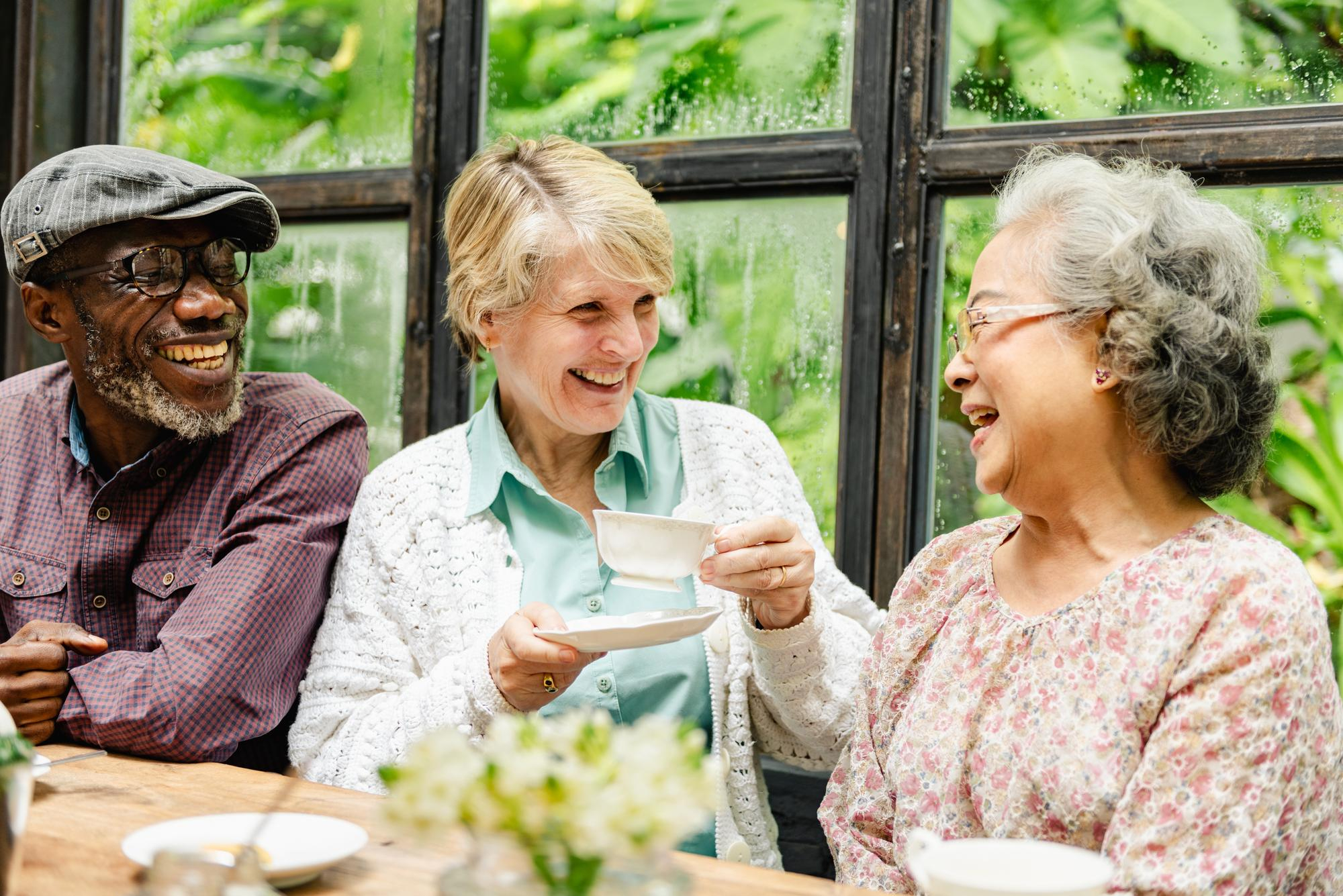 Diverse seniors laughing over tea at Affinity Care Assisted Living
